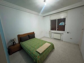 A bedroom with a single bed, a nightstand, a window, and a radiator. - Apartment with 3 bedrooms (Tunis)