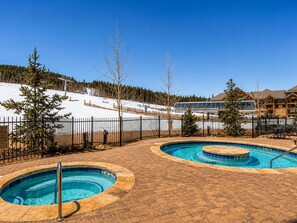 Ein Resort mit Poolbereich, einem Skilift im Hintergrund und einem Gebäude mit vielen Fenstern.