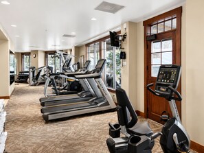 Ein Fitnessstudio mit Laufbändern, Crosstrainern und einem Ergometer.