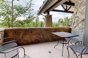 An outdoor patio with stone walls, metal chairs, and a table. - Crystal Peak Lodge 7006 ~ Ski-in/Ski-out ~ NEW LISTING ~ By CoralTree Residences (Breckenridge)
