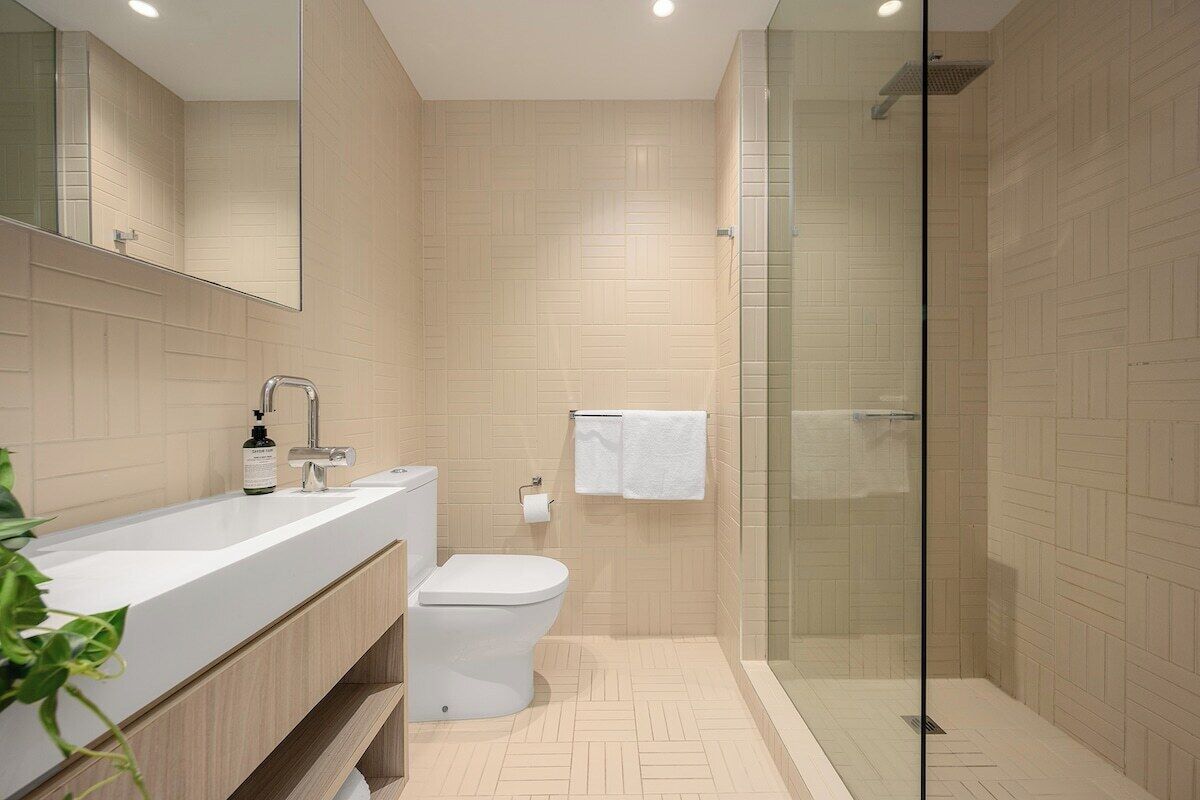 A modern bathroom with a glass shower enclosure, a white sink, and a toilet.