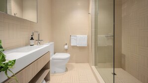 Ein modernes Badezimmer mit Duschkabine aus Glas, einem weißen Waschbecken und einer Toilette.