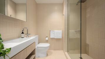A modern bathroom with a glass shower enclosure, a white sink, and a toilet.