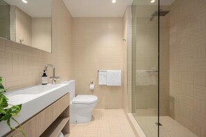 A modern bathroom with a glass shower enclosure, a white sink, and a toilet. - Panoramic City View, Stunning 3BR Pool & Gym & Parking (South Yarra)