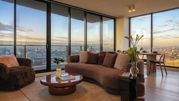 A modern living room with a large window, a brown sofa, a coffee table, and a small side table with a vase.