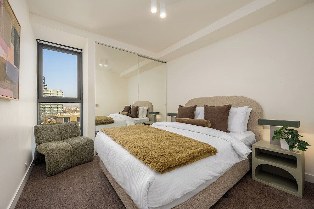 Ein modernes Hotelzimmer mit einem großen Bett, einer Sitzecke und Blick durch eine Glastür.