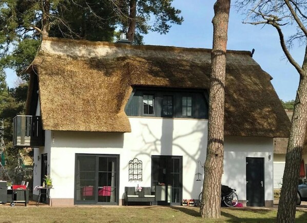 Ein Haus mit einem Strohdach, großen Fenstern und einer sichtbaren Garagenöffnung.