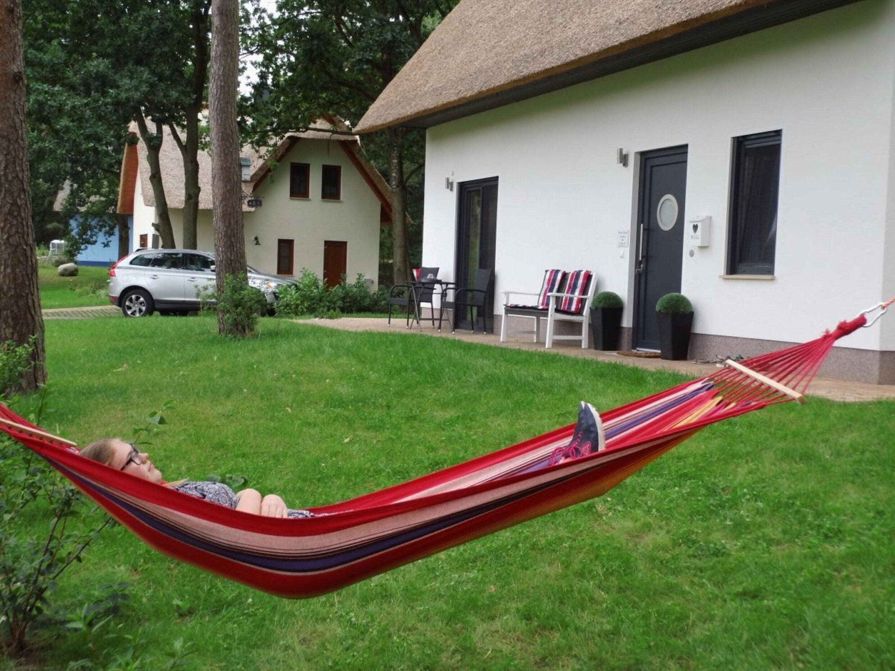 Een hangmat in een gazon, met een wit gebouw op de achtergrond.