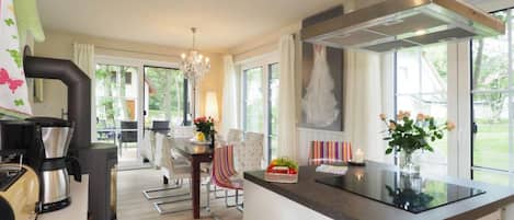 A modern kitchen with a central island, a dining area with a chandelier, and a view of the outdoors.