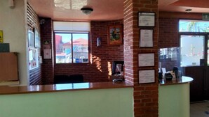 Una zona de recepción con pared de ladrillo, certificados enmarcados y ventana con vista a edificios.