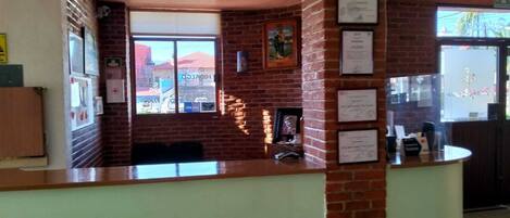 A reception area with a brick wall, framed certificates, and a window with a view of buildings.