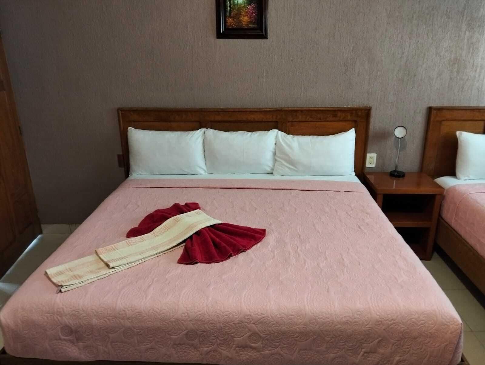 A hotel room with a bed, two bedside tables, and a nightstand.