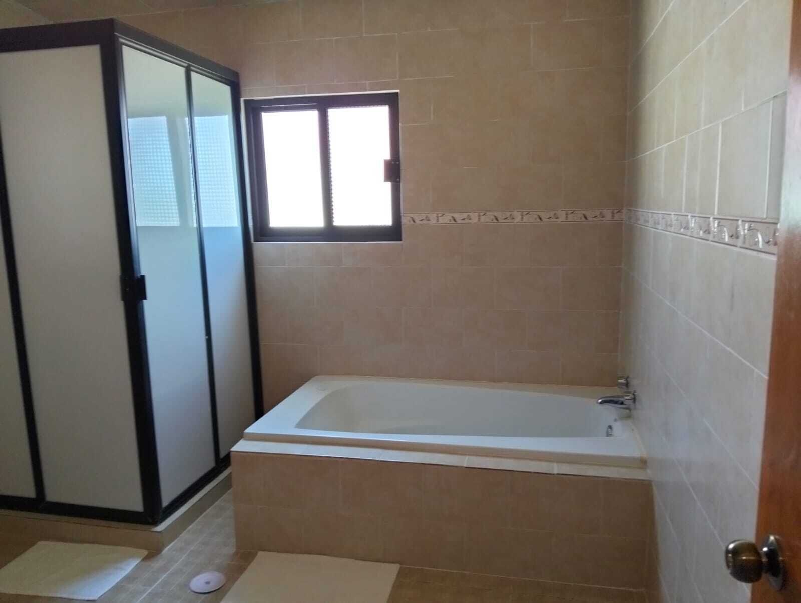 A bathroom with a bathtub, a shower enclosure, and a window.