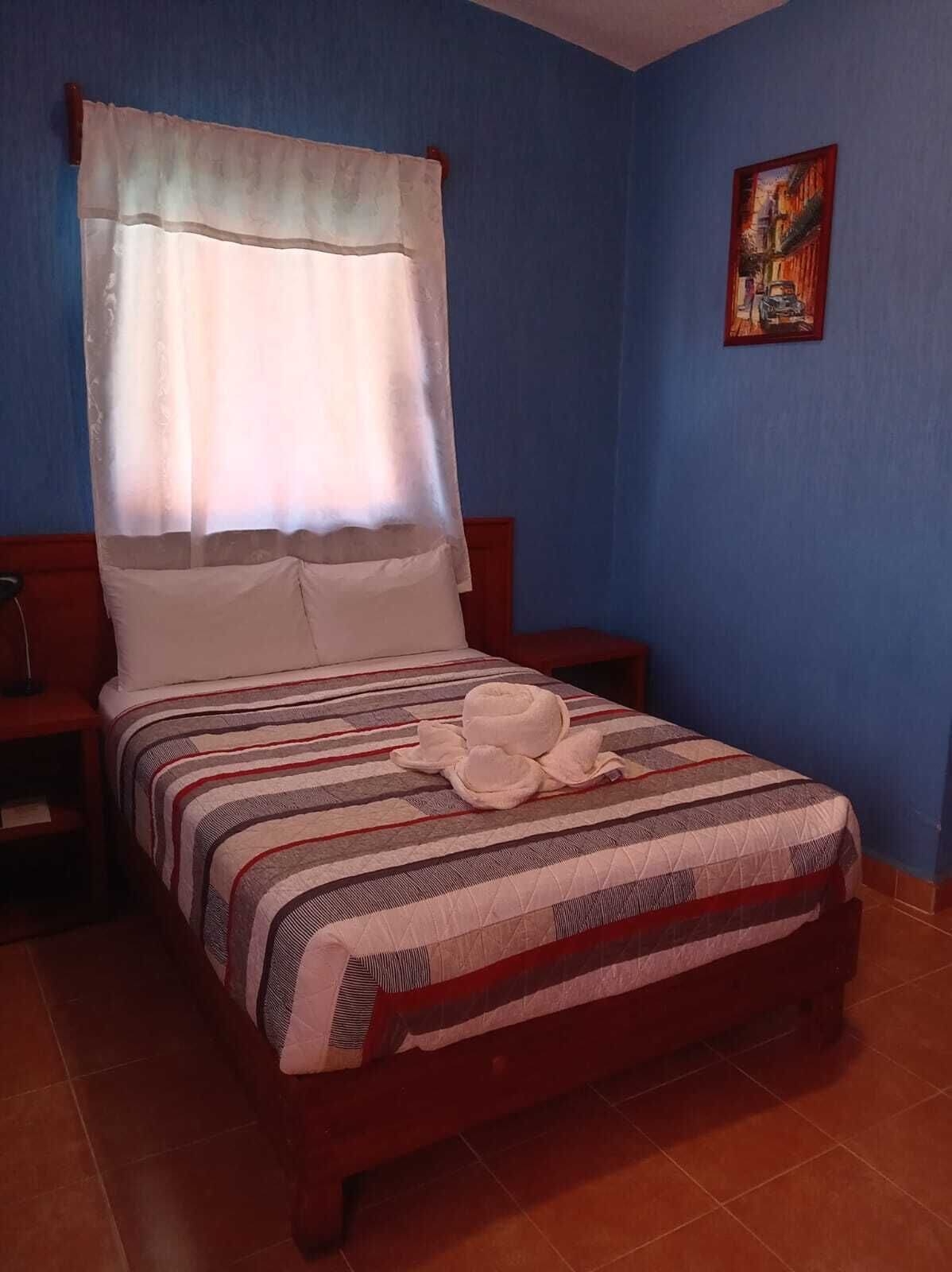 A bed with a striped bedspread, a white pillow, and a white canopy.