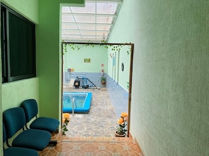 Un pasillo con zona de piscina, sillas y plantas en macetas.
