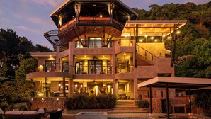 A multi-story building with a pool, outdoor seating, and a balcony.