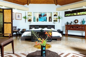 Un dormitorio moderno con una cama grande, mesitas de noche, un jarrón decorativo con flores y un cabecero de madera.
