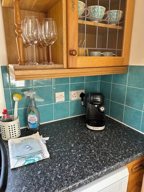 Eine Küche mit einer Kaffeemaschine, einer Spülmittelflasche und einem Zahnbürstenhalter auf der Arbeitsfläche.