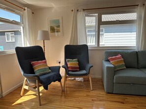 A room with two armchairs, a sofa, a lamp, and a window with curtains.