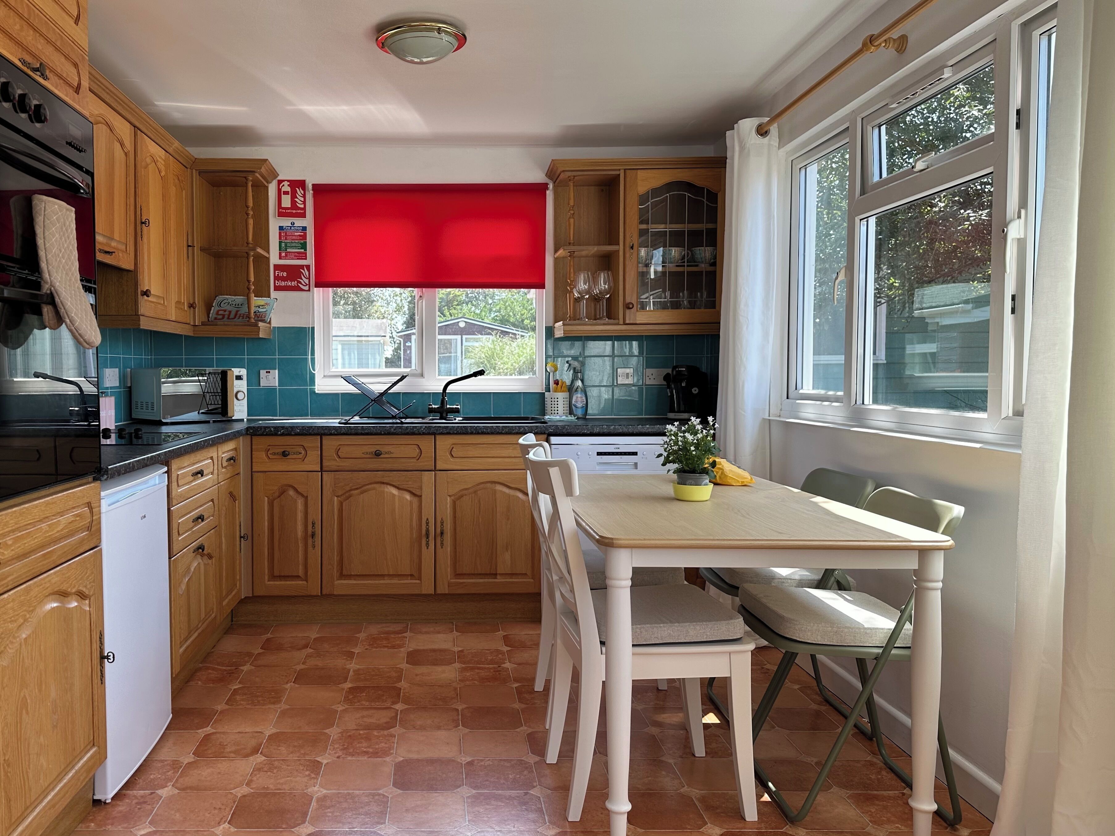 Una cucina con mobili in legno, un forno a microonde, un lavello e un tavolo da pranzo con sedie.