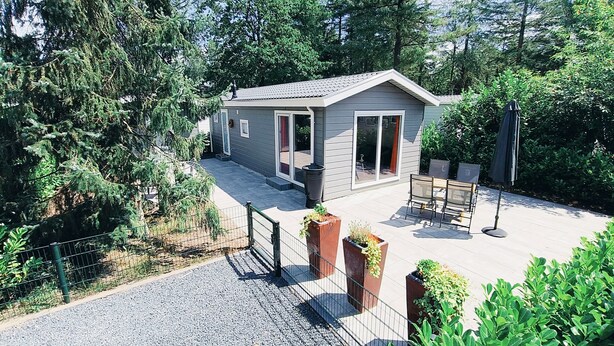 A small house with a covered patio, a fenced yard, and a gravel driveway. - Our Beautiful new Chalet Vogelzang for Retreat (Vorden)