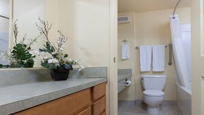 Une salle de bain comprenant des toilettes, une douche et un lavabo avec un miroir au-dessus.