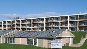 Un hôtel à plusieurs étages, avec une enseigne indiquant « Surfside Inn », et un bâtiment doté d’un toit en pente.
