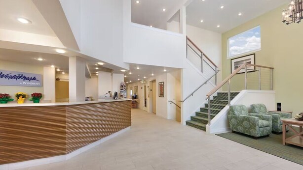 Un hall d’entrée spacieux comprenant un comptoir d’accueil, un escalier et un espace détente.