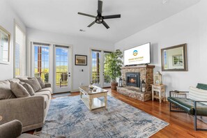 A spacious living room with a fireplace, a ceiling fan, and a television mounted on the wall. - Silver Dollar Awesome 2BDR (Branson)