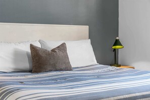 A bed with a striped bedspread, a pillow, and a nightstand with a lamp. - Silver Dollar Awesome 3BDR (Branson)