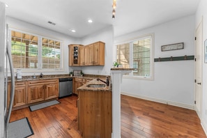 A kitchen with wooden cabinets, a granite countertop, and a built-in dishwasher. - Silver Dollar Awesome 2BDR (Branson)