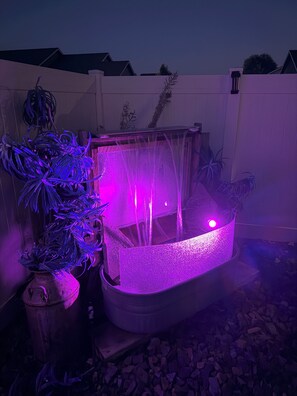 A hot tub with a water feature and a plant arrangement.