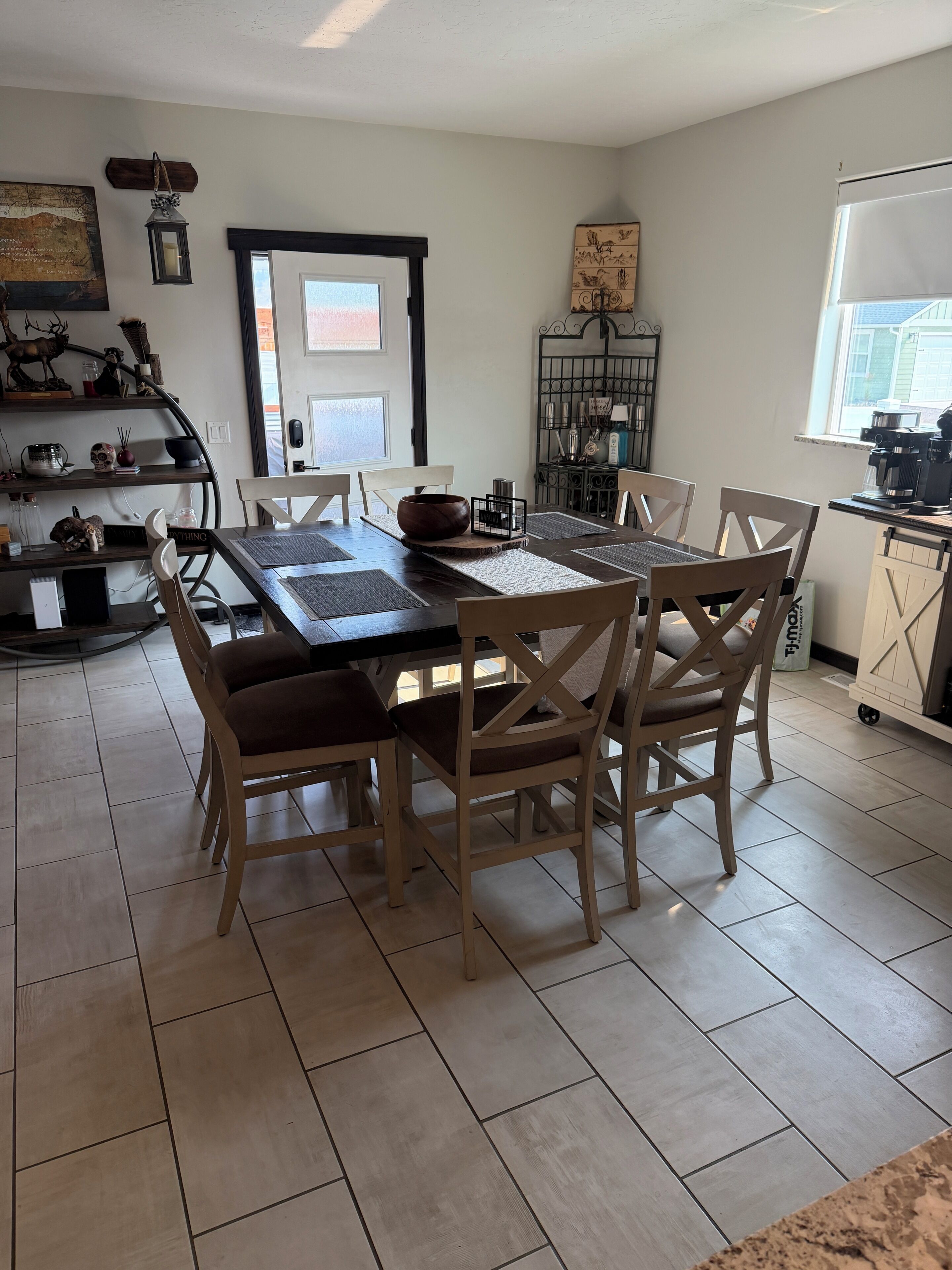 A dining area with a wooden table and chairs, a kitchen area with appliances, and a view of the outside.