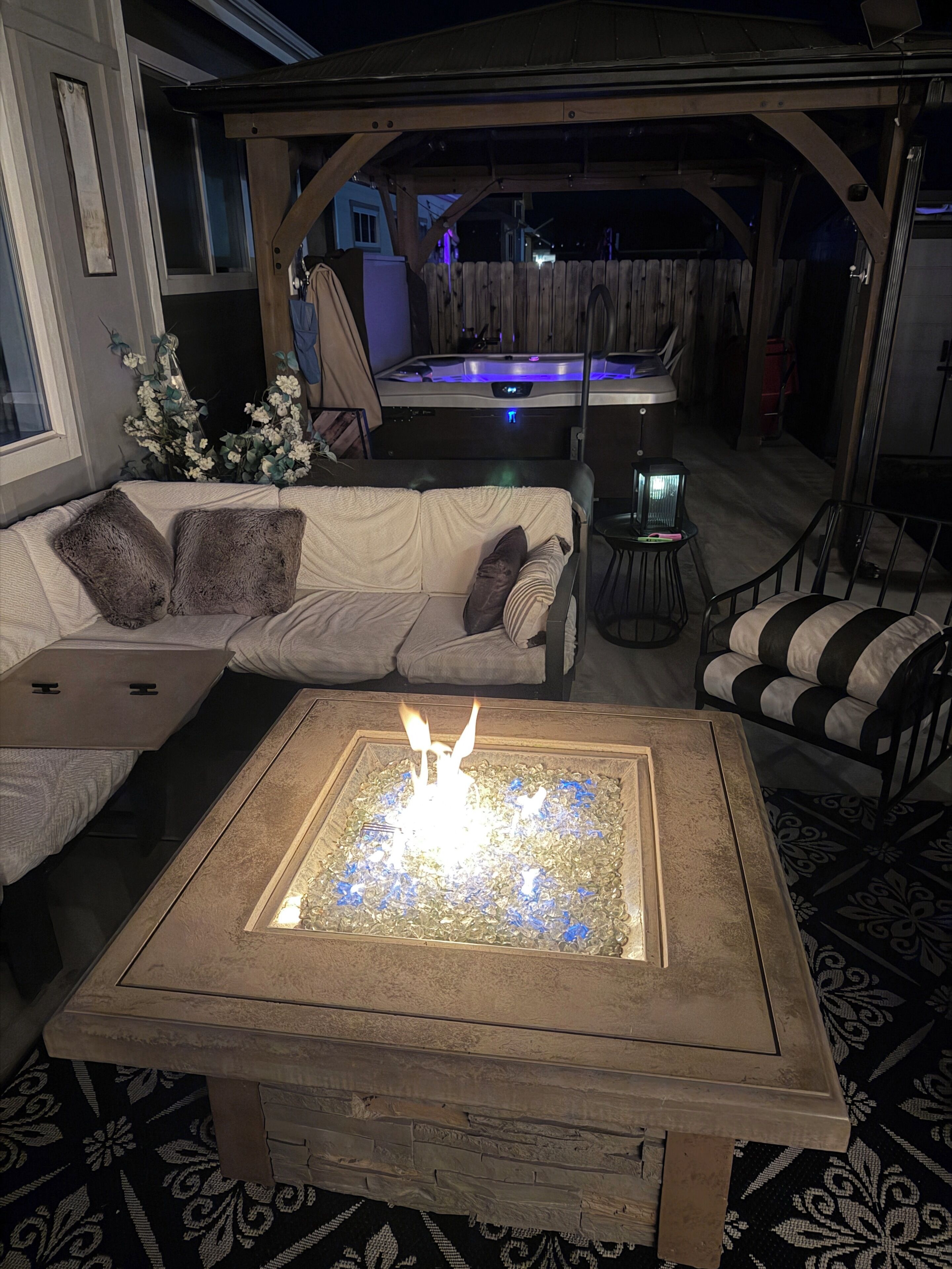 Un espacio al aire libre acogedor con una chimenea, un sofá, una silla y una mesa.