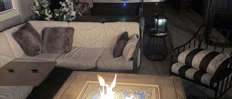 A cozy outdoor seating area with a fire feature, a sofa, a chair, and a table.