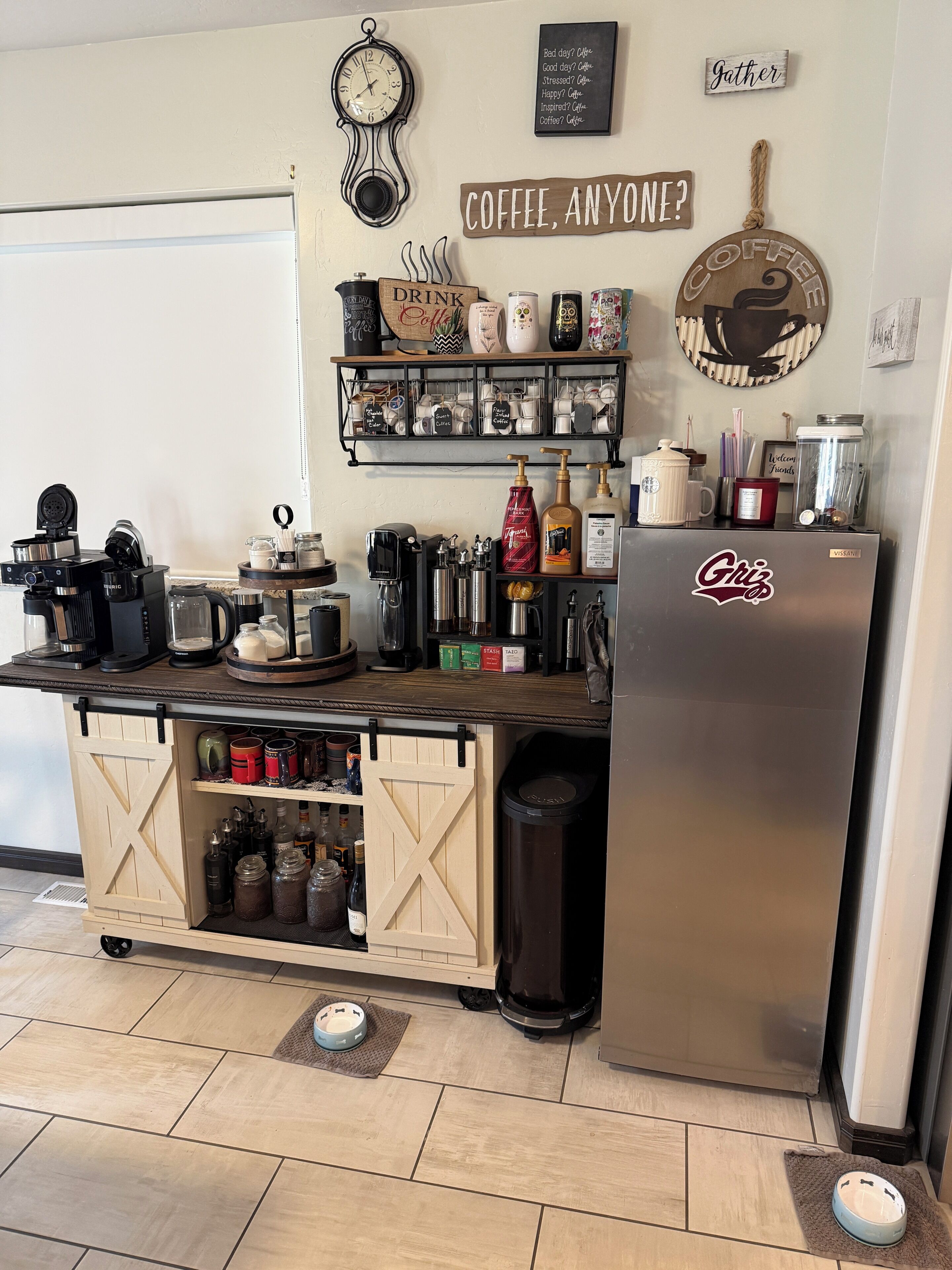 Una cucina con angolo caffè, una sveglia e un cartello che dice 'Caffè, qualcuno?'