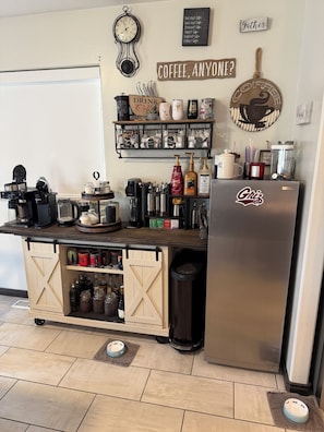 Una cocina con estación de café, un reloj y un cartel que dice '¿Café para alguien?'
