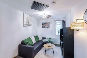 A modern living room with a grey sofa, a round coffee table, and artwork on the walls. - 2 Bed | 7 Min to City Centre | Free Parking (Manchester)