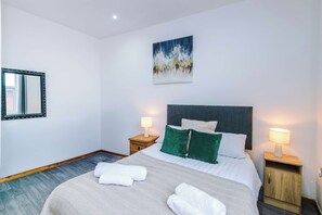 A hotel room with a bed, two bedside tables with lamps, a painting on the wall, and a mirror on the left. - 2 Bed | 7 Min to City Centre | Free Parking (Manchester)