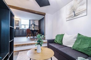 A modern living room with a sofa, a coffee table, and a dining area in the background. - 2 Bed | 7 Min to City Centre | Free Parking (Manchester)