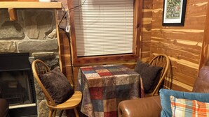 A cozy cabin interior with a stone fireplace, wooden walls, a quilted table, and leather furniture. - Adorable 1-bedroom cabin in Treat, Arkansas.  2 adults, no pets, 2 night minimum (Dover)