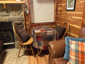 A cozy cabin interior with a stone fireplace, wooden walls, a quilted table, and leather furniture. - Adorable 1-bedroom cabin in Treat, Arkansas.  2 adults, no pets, 2 night minimum (Dover)