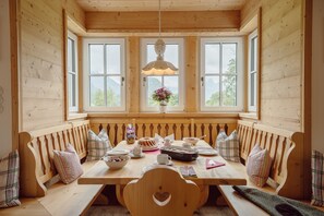 Ein Essbereich aus Holz mit einer Bank, einem Tisch und einer hängenden Leuchte.