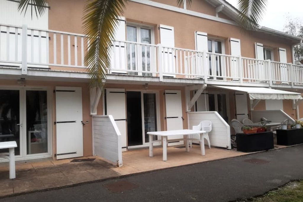 A two-story building with a balcony, a patio with outdoor furniture, and a door with a glass panel.