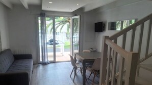 En moderne stue med sofa, spisebord, stole og en trappe.