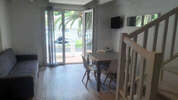 Een moderne woonkamer met een bank, eettafel, stoelen en een trap.