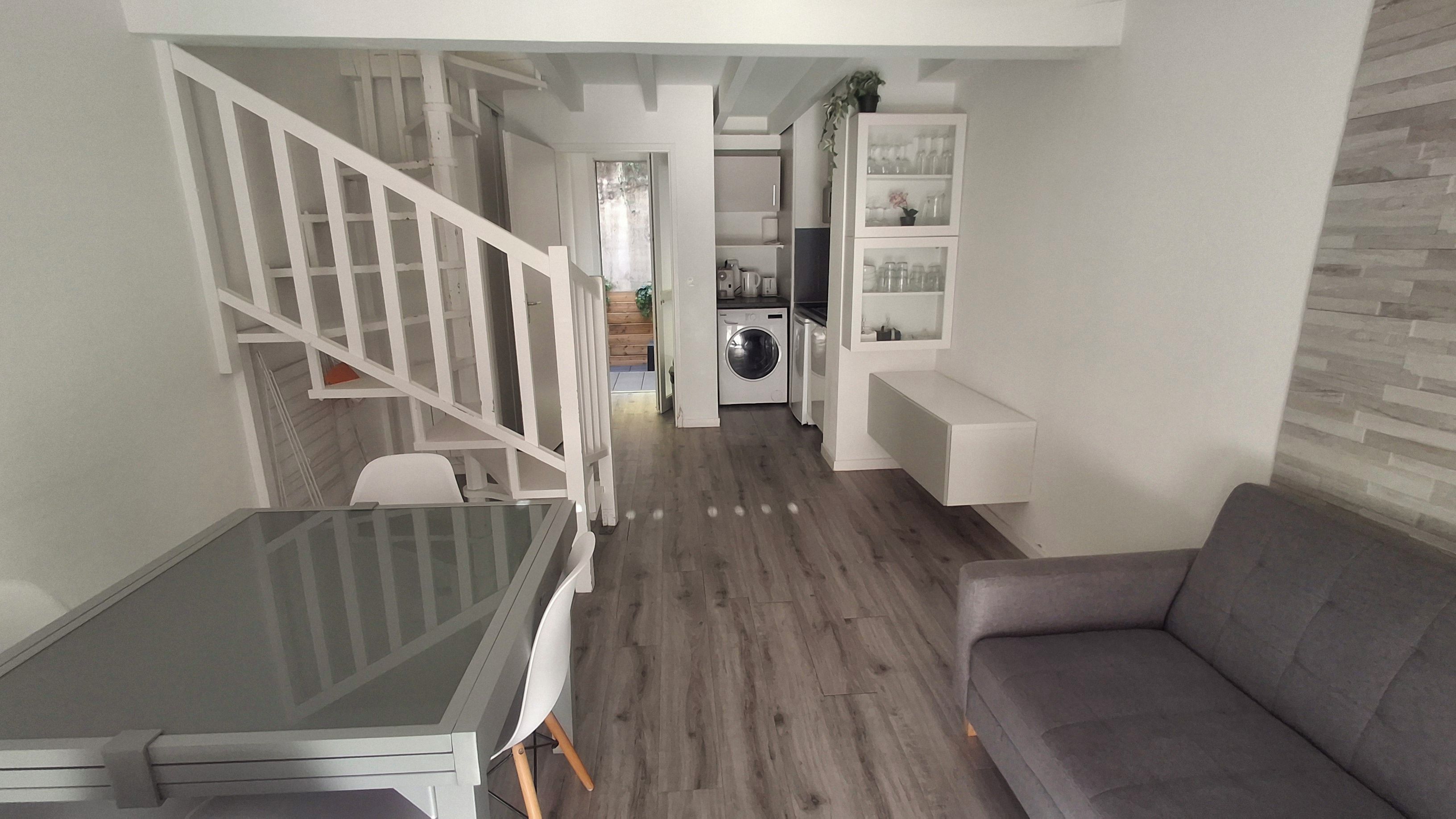 A modern living space with a dining table, sofa, staircase, and built-in shelving.
