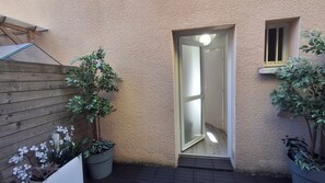 Una valla de fusta, una planta en test i una porta amb finestre.