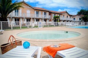 Ein Poolbereich mit Liegestühlen, einem kleinen Pool und einem Gebäude mit Balkonen.