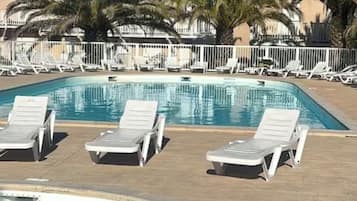 Piscina com espreguiçadeiras e cerca branca.